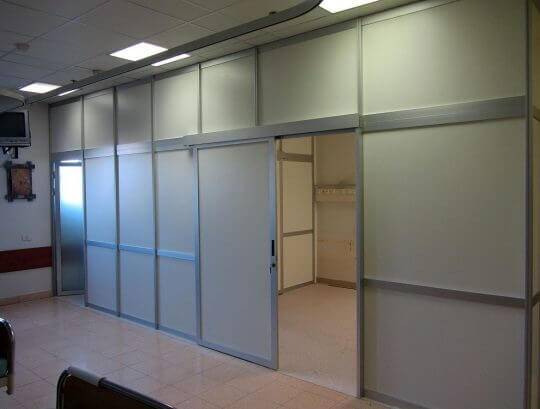 מחיצות רצפה תקרה לסגירת אזור רופאים במילוי HPL כולל דלתות הזזה ודלתות ציר.